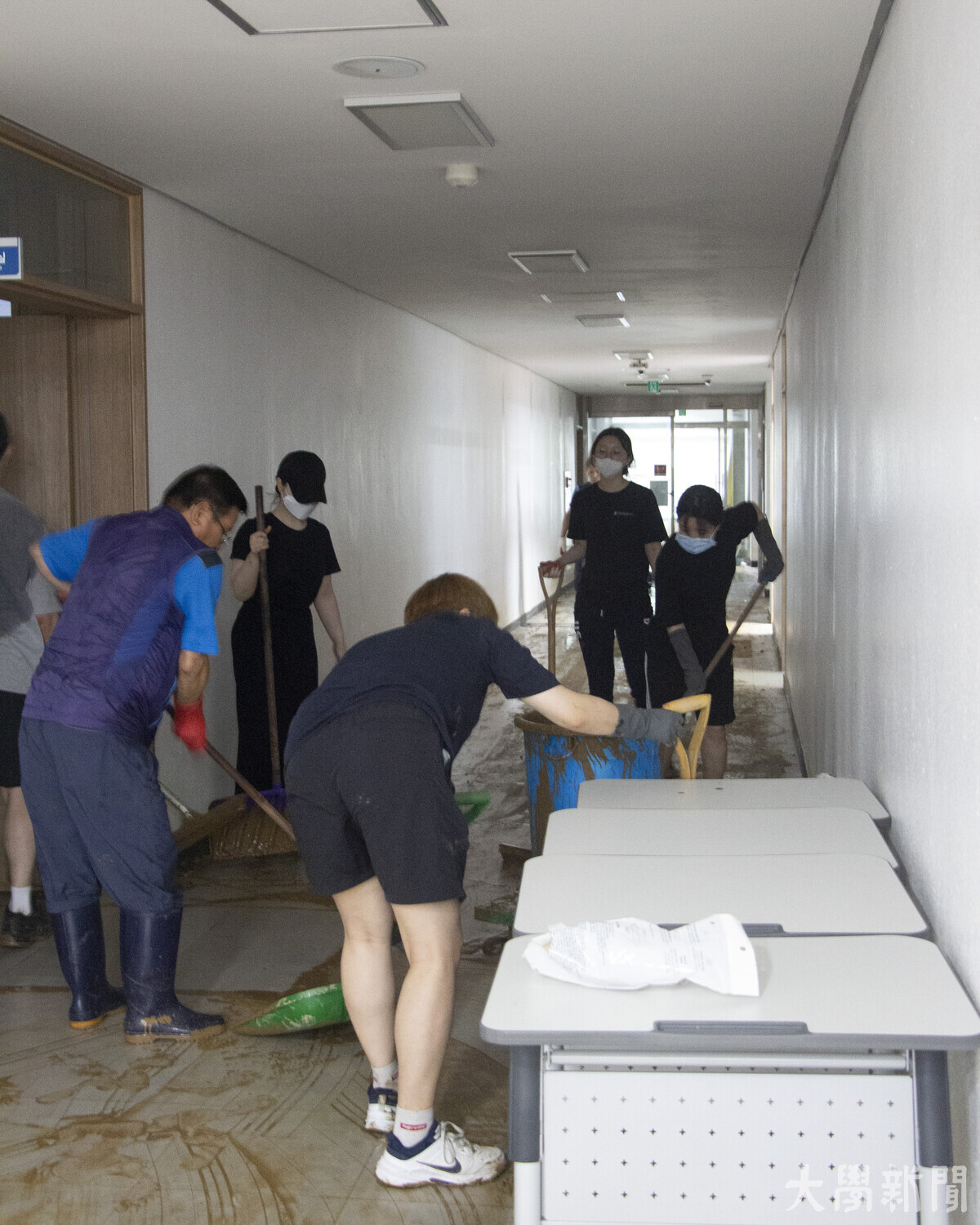 자원봉사자들이 복도에 쌓인 진흙을 삽으로 퍼 정리하고 있다.
